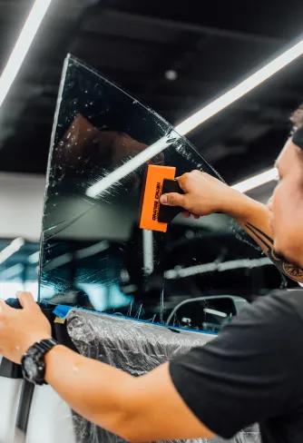 DEIZ installer smoothing film on a window with a squeegee