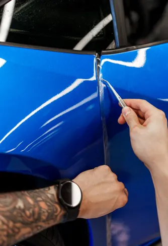 DEIZ installer tucking film into a door gap on a blue Lamborghini