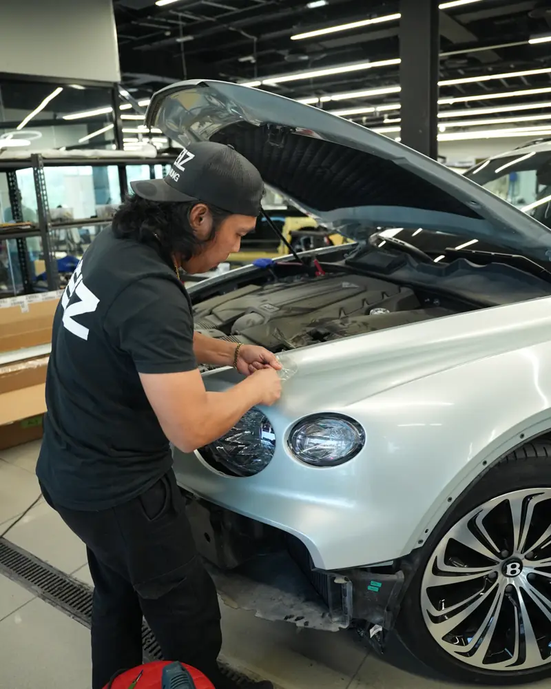 DEIZ technician installing wrap film on the front of a Bentley Bentayga